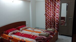 Un dormitorio con cama, almohadas, manta, espejo y una puerta.