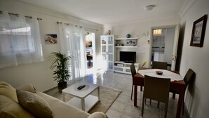 A living room with a sofa, coffee table, TV, and dining area with chairs and a table. - Casa Bonita - Big terrace close to the beach (Lomo Quiebre)