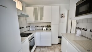 A compact kitchen with white cabinets, a built-in oven, a coffee maker, and a microwave. - Casa Bonita - Big terrace close to the beach (Lomo Quiebre)