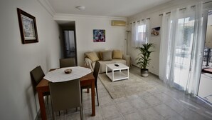 A living room with a dining table, chairs, a sofa, and a coffee table. There is a potted plant and a painting on the wall. - Casa Bonita - Big terrace close to the beach (Lomo Quiebre)