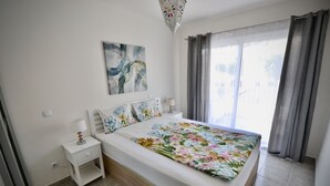 A bedroom with a bed, nightstands, a lamp, a painting, and a window with curtains. - Casa Bonita - Big terrace close to the beach (Lomo Quiebre)