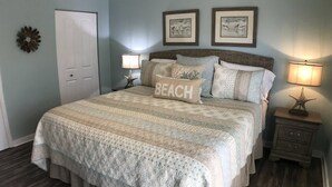 A bedroom with a large bed, two bedside lamps, a starfish decoration, and a door. - Beautiful-condo-townhouse- Sleeps 8 - 8 Minute walk to Beach - Near Pier Park (Panama City Beach)