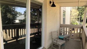 A balcony with a table and chairs, a sliding glass door, and a black wall-mounted light fixture. - Beautiful-condo-townhouse- Sleeps 8 - 8 Minute walk to Beach - Near Pier Park (Panama City Beach)