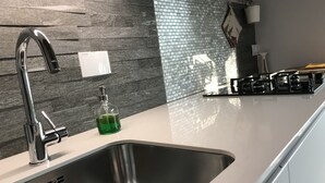 A modern kitchen with a stainless steel sink, a faucet, and a soap dispenser.