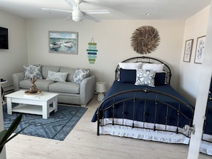 A bedroom with a bed, a sofa, a coffee table, a painting, and a wall decoration. - 100 Steps to the beach with a heated pool!! (North Wildwood)