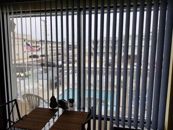 A balcony with vertical blinds, a table, and chairs. - 100 Steps to the beach with a heated pool!! (North Wildwood)