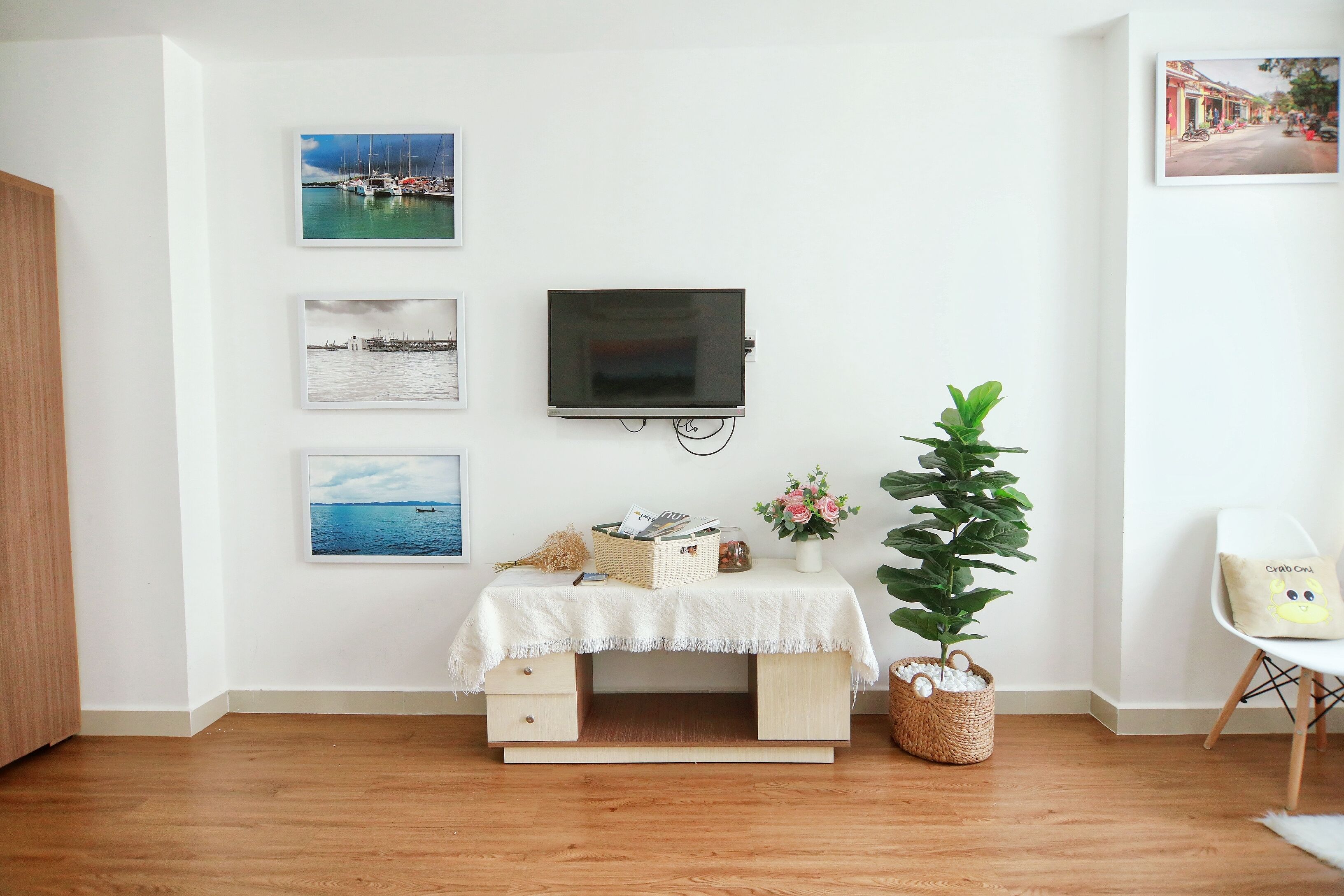 A room with a wooden desk, a television, and three framed pictures on the wall.