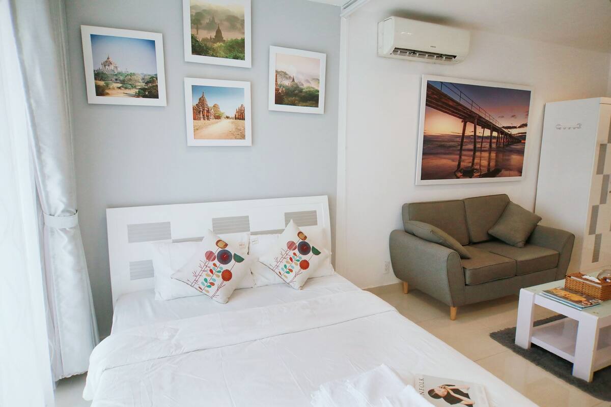 A neatly arranged bedroom with a bed, a sofa, and a small table.