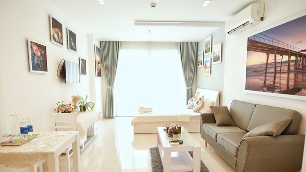 A modern living room with a sofa, coffee table, and a dining area with a table and chairs. - Jolie Home - Sky Center - Block A (Ho Chi Minh City)