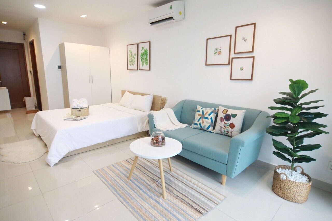 Un dormitorio moderno con una cama, un sofá, una mesita redonda y una planta en maceta.