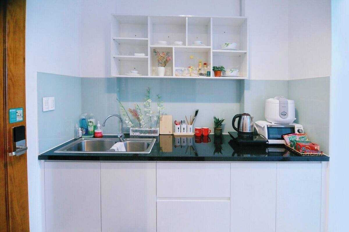 A kitchen with white cabinets, a black countertop, and various kitchen items.