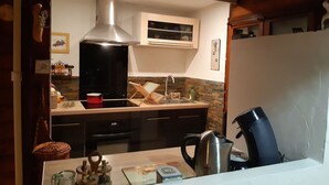 A modern kitchen with a stainless steel range hood, a built-in oven, and a sink. There is a wooden countertop with various kitchen items and a kettle. - Chalet surrounded by nature 2.5 km from BEDOIN (Bédoin)