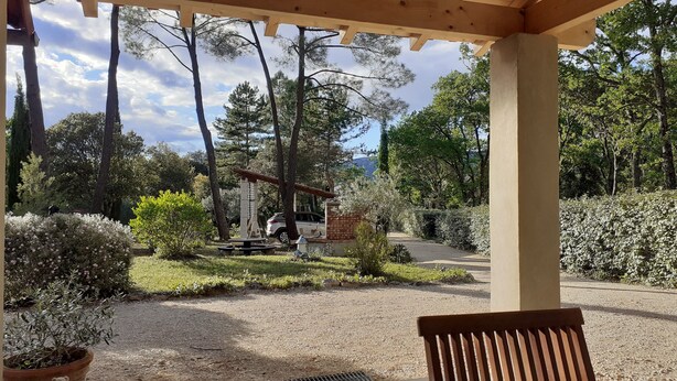 A covered outdoor area with a gravel path, wooden benches, and a variety of plants and trees. - Chalet surrounded by nature 2.5 km from BEDOIN (Bédoin)