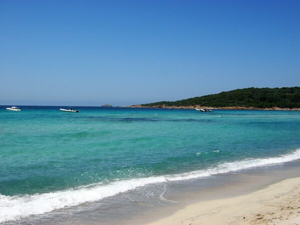 Ranta lähistöllä, aurinkotuoleja, rantapyyhkeitä