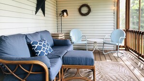 A cozy porch with a blue sofa, wicker chairs, and a small table. - Lummis St. Bungalow located in the quaint township of Sodus Point NY! (Sodus Point)