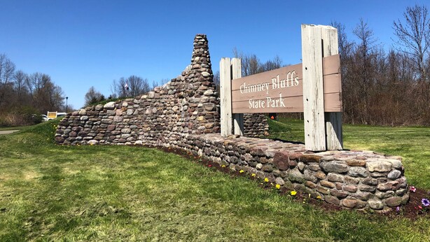 A stone wall with a wooden sign that reads "Chimney Bluffs State Park". - Lummis St. Bungalow located in the quaint township of Sodus Point NY! (Sodus Point)