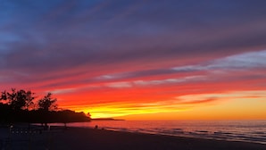 A beach with a sunset, silhouettes of trees, and a calm sea. - Lummis St. Bungalow located in the quaint township of Sodus Point NY! (Sodus Point)