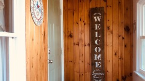A wooden interior with a welcome sign, a door, and a patterned doormat. - Lummis St. Bungalow located in the quaint township of Sodus Point NY! (Sodus Point)