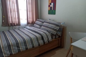 Een enkel bed met gestreept beddengoed, een klein nachtkastje en een stoel.