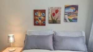 Une chambre à coucher avec un lit, une table de chevet avec une lampe et trois tableaux accrochés au mur.