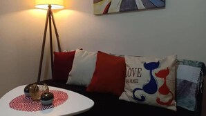 Un salon chaleureux avec une table basse ronde, un lampadaire et un canapé agrémenté de coussins à motifs.