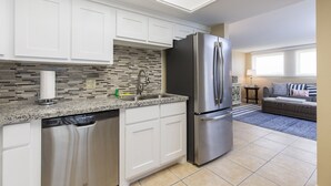 A modern kitchen with white cabinets, a stainless steel refrigerator, and a tiled backsplash.