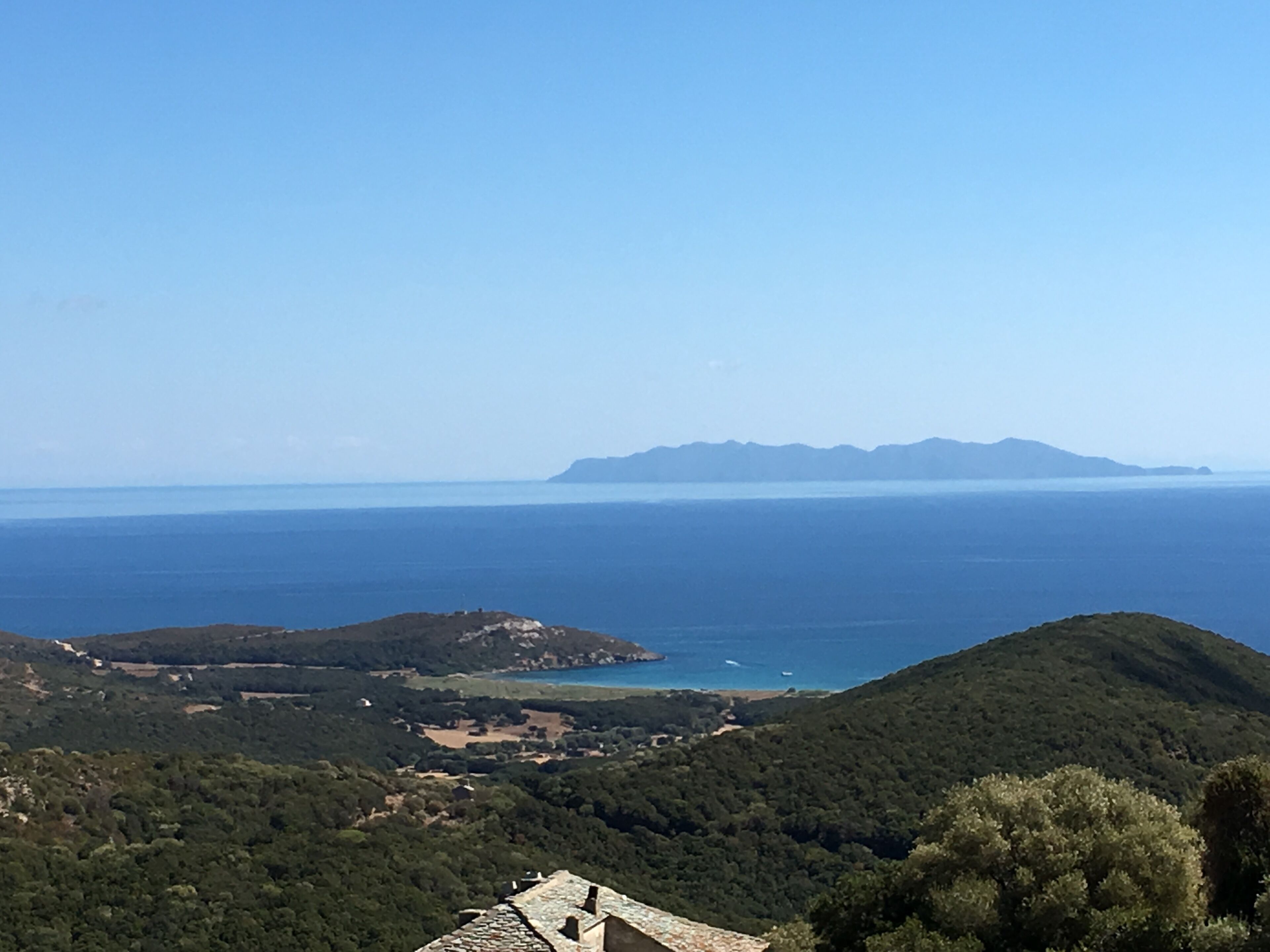 Paisaje costero con vista al mar y montañas distantes.