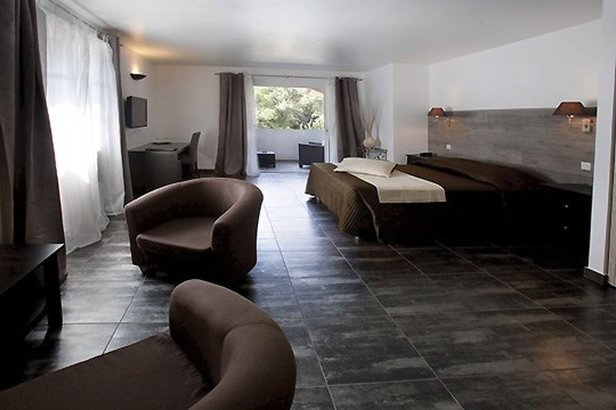 Una habitación de hotel moderna con sofá, cama, una mesita y televisor.