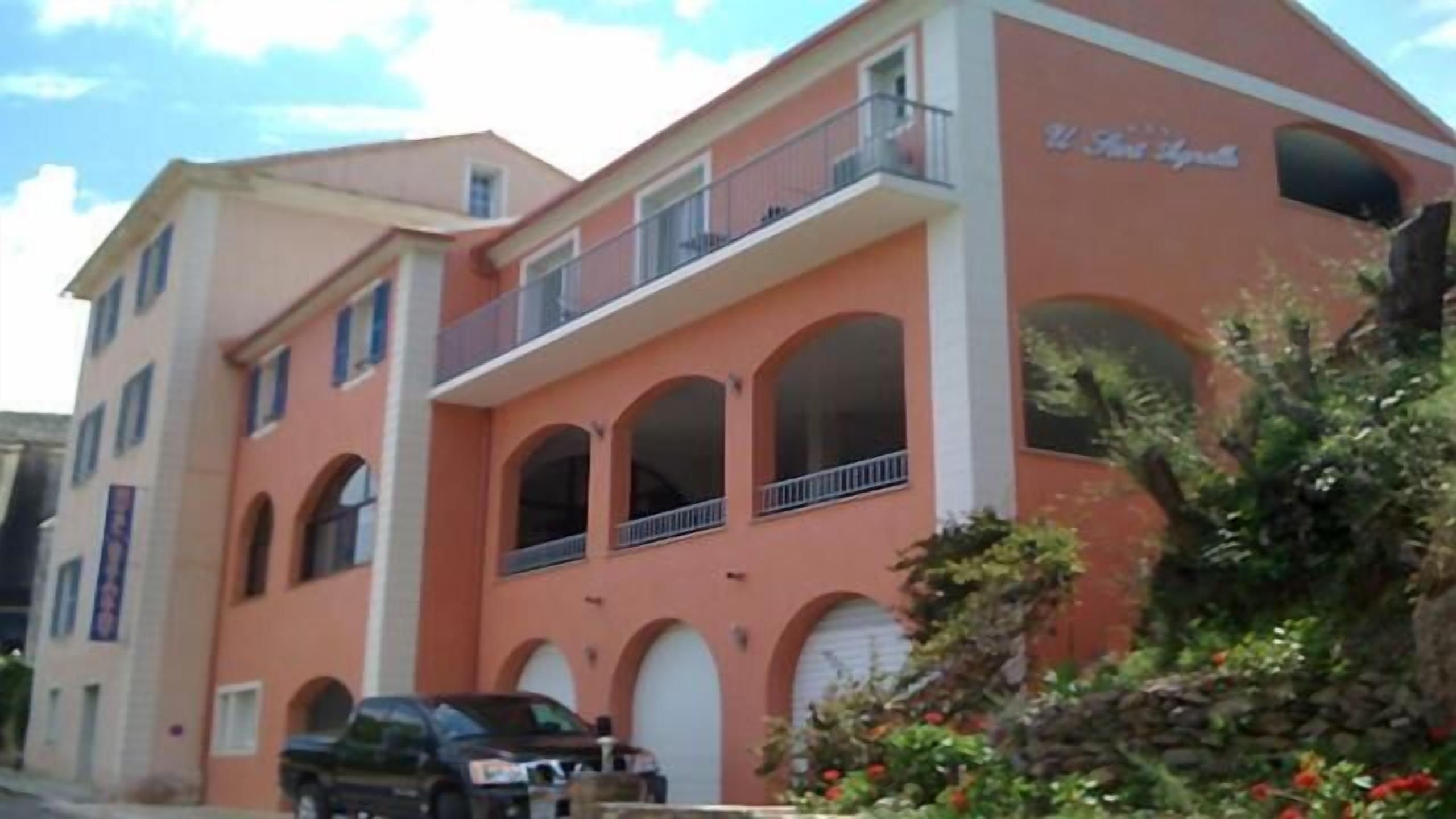 A multi-story building with a pink facade, arched windows, and a balcony on the upper floor.
