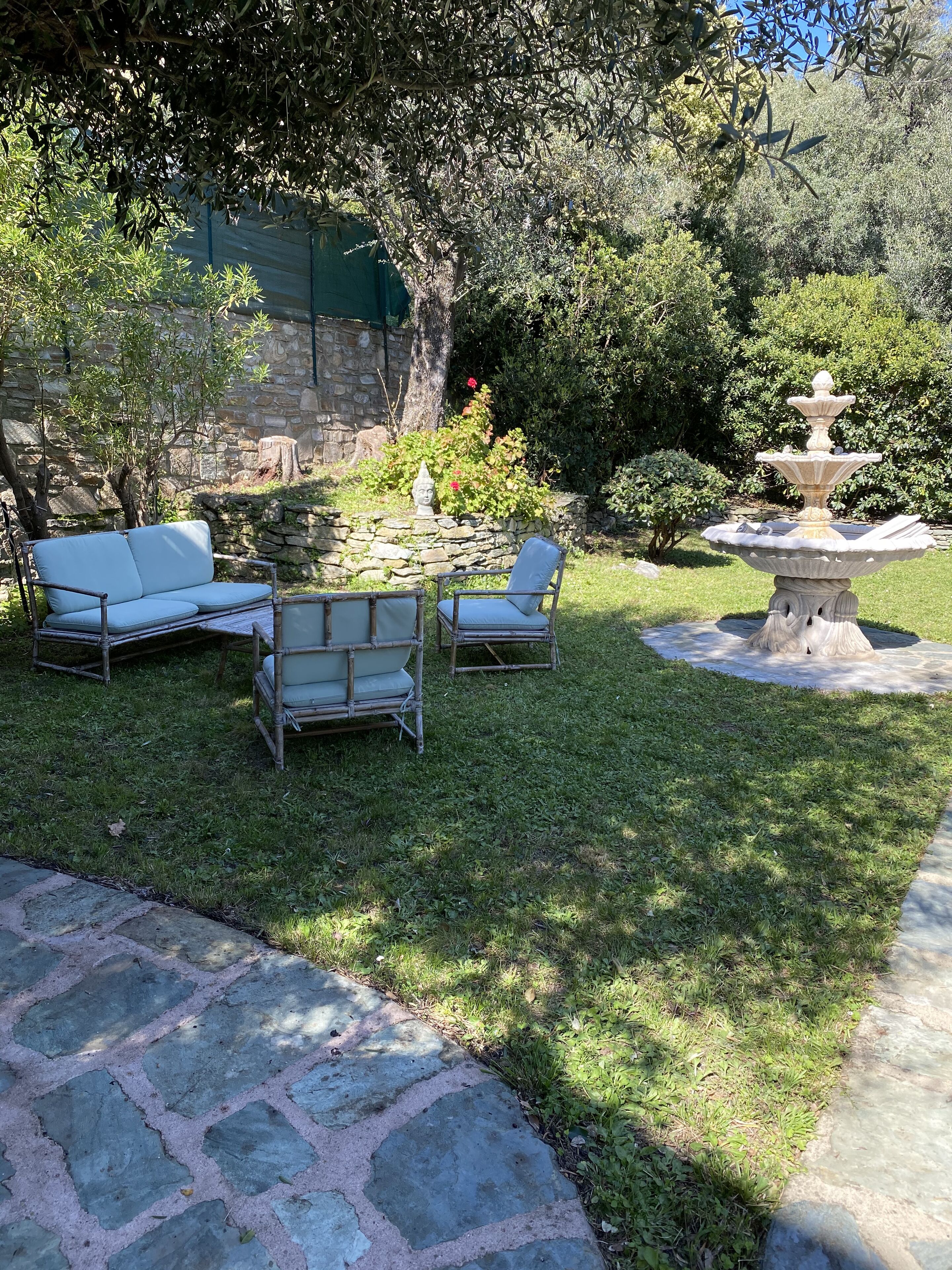 A garden with a stone wall, a fountain, and outdoor seating.