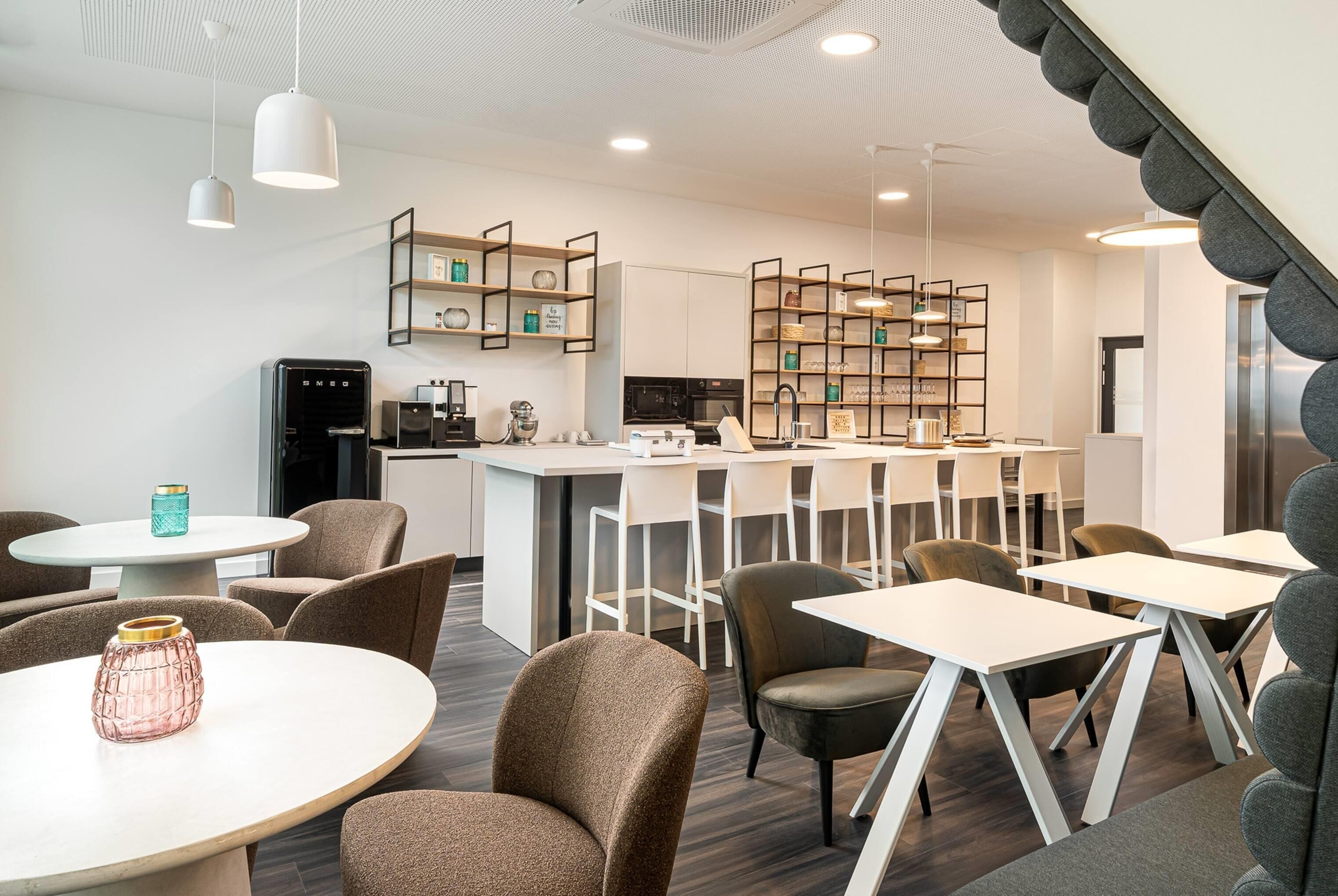Ein modernes Interieur mit runden Tischen, Barhocker und einer Küchenzeile.