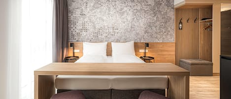 Una habitación de hotel moderna con una cama de madera, una mesita, dos sillas, un papel tapiz decorativo y un armario con espejo.