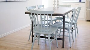 Comedor con mesa rectangular, seis sillas, una araña de techo, una obra de arte de mármol en la pared y una planta en maceta.