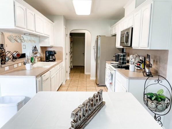 A kitchen with white cabinets, a stainless steel refrigerator, and a coffee maker.