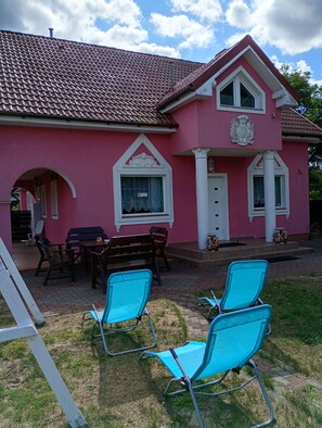 A pink house with a tiled roof, a porch with chairs, and a number '3A' on the wall. - Pink holiday house 10 pers. between lagoon and heather in the bird sanctuary (Nowe Warpno)