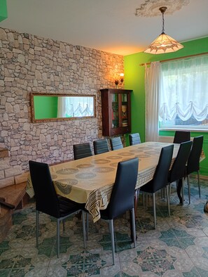 A dining area with a stone wall, a large mirror, a cabinet with books, and a table with chairs. - Pink holiday house 10 pers. between lagoon and heather in the bird sanctuary (Nowe Warpno)