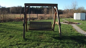 A wooden swing set in a grassy field with a clear sky. - Pink holiday house 10 pers. between lagoon and heather in the bird sanctuary (Nowe Warpno)