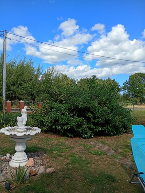 A garden with a white statue, a blue pool, and a hedge.