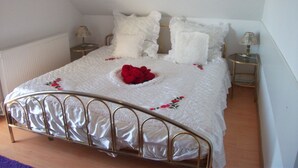 A neatly made bed with white bedding and a metal frame, two bedside tables with lamps, and a wooden floor. - Pink holiday house 10 pers. between lagoon and heather in the bird sanctuary (Nowe Warpno)