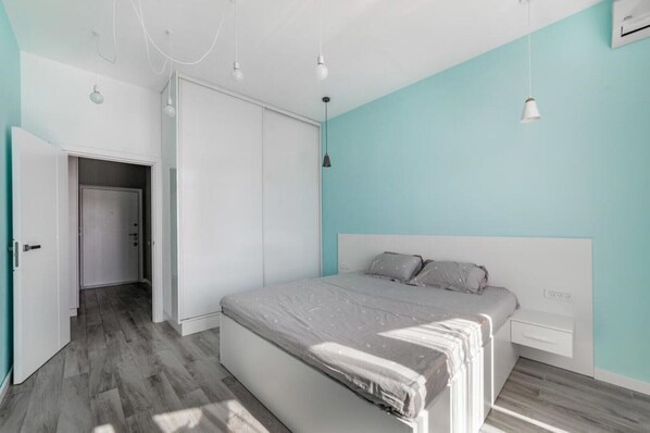 A bedroom with a bed, a wardrobe, a door, and a light fixture.