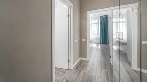 A hallway with a white door, a glass partition, and a view into a bedroom with a bed and curtains. - Sunset lovers in Odessa (Odessa)