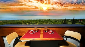 A table with two chairs and two cups of tea, overlooking a scenic landscape with a sunset. - Seaview family apartment at Olympus - PanoramaLoft (Litochoro)