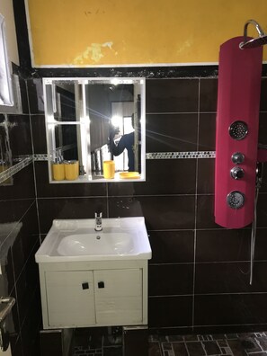 A bathroom with a white sink, a mirror, and a red shower enclosure. - Residence meublée The Boss (Abidjan)