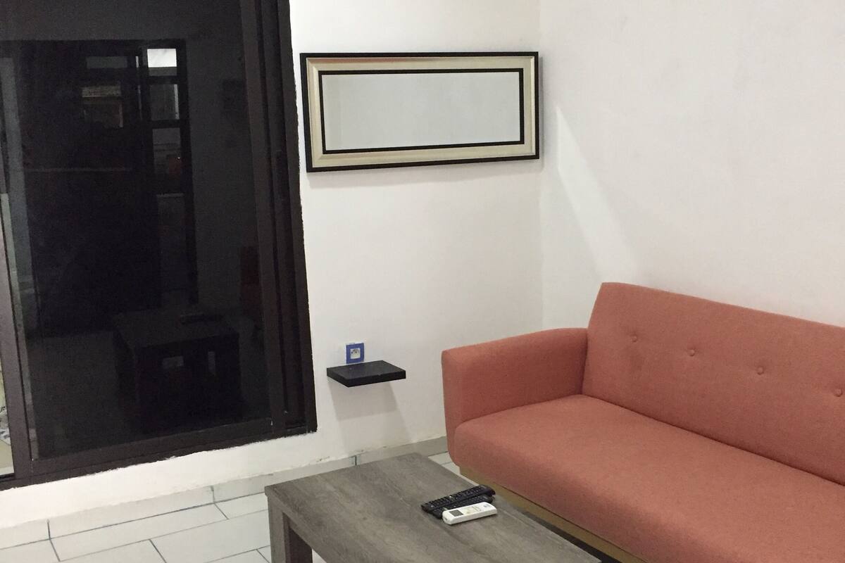 Una sala de estar con un sofá, una mesita, un cuadro enmarcado y una puerta.