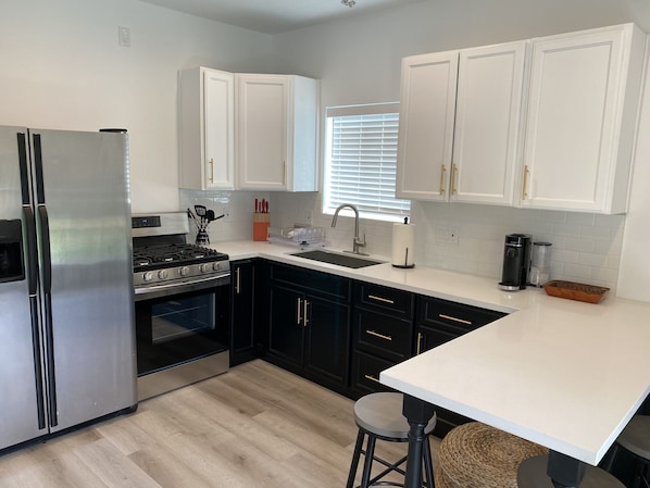 A modern kitchen with stainless steel appliances, black cabinets, and a white countertop.