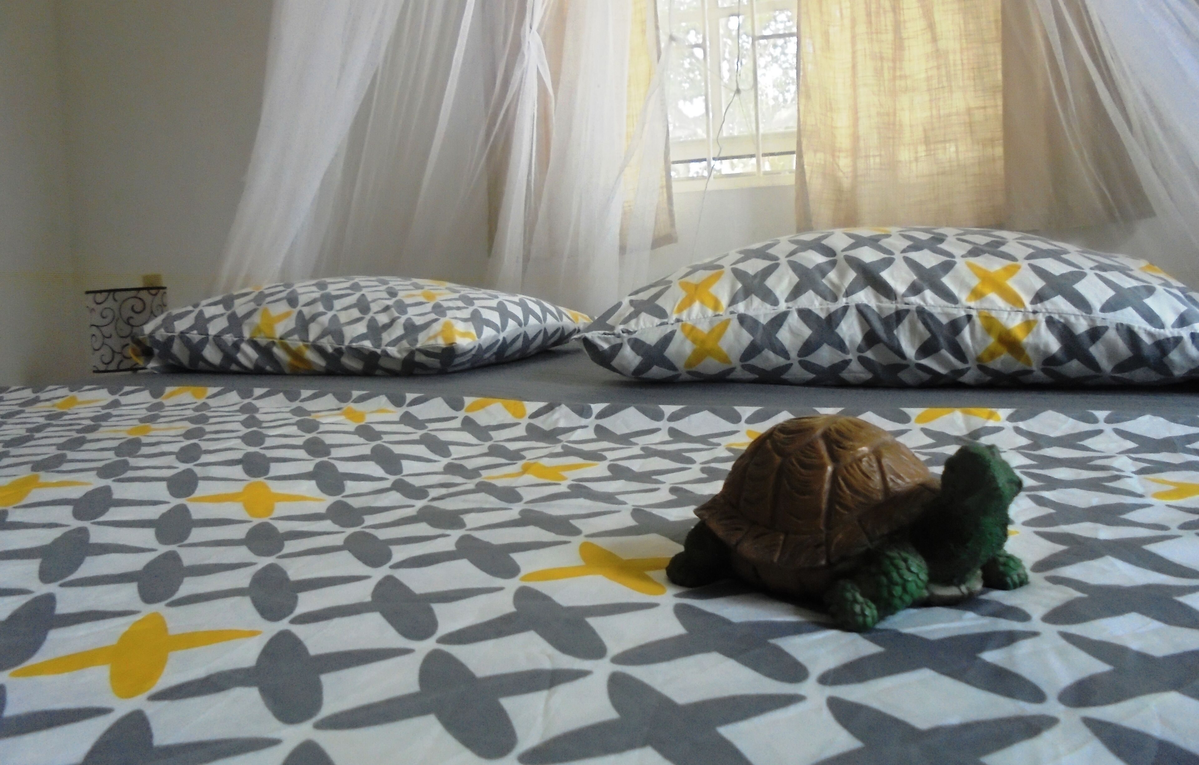 Una cama con ropa de cama estampada y un juguete de tortuga.