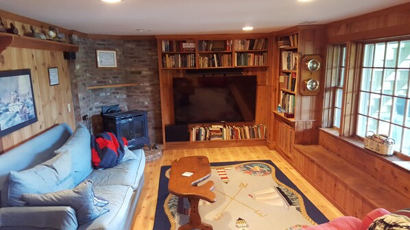 Un salon chaleureux avec une cheminée, un canapé, une table basse et une bibliothèque remplie de livres.