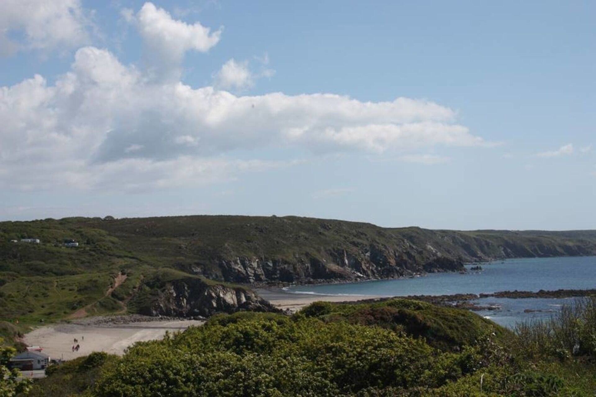 Un paysage côtier avec une plage, des falaises et un ciel dégagé.