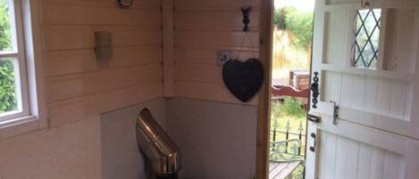 A corner room with a wooden door, a small bench, and a heart-shaped decoration on the wall.