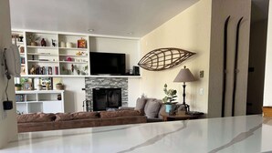 Ein modernes Wohnzimmer mit Kamin, Fernseher und einer Couch.
